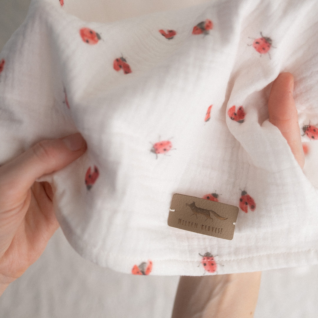apró, ismétlődő mintás textil kendő egy női kézben